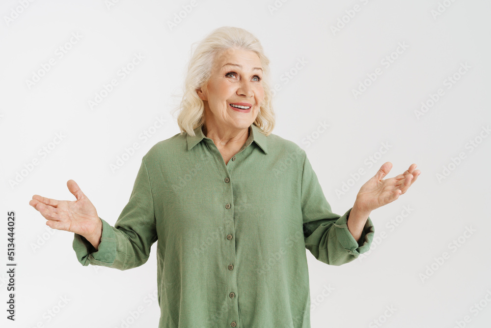 Grey senior woman in shirt smiling while gesturing at camera Grey senior woman in shirt smiling while gesturing at camera