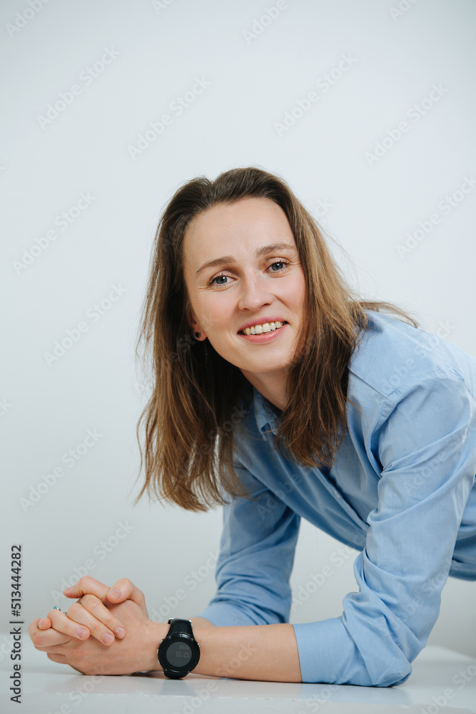 Leaning on a table smiling business woman in blue dress shirt with long hair Leaning on a table smiling business woman in blue dress shirt with long hair