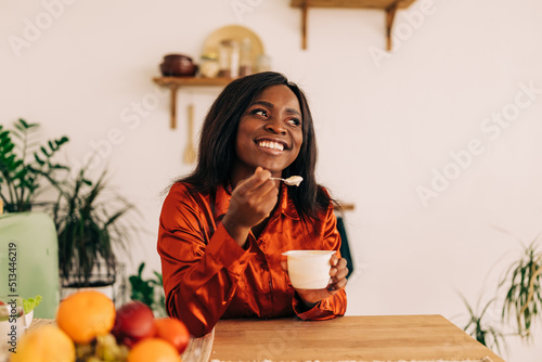 Beautiful young woman eating yogurt in the kitchen in the morning. Healthy food. Portrait shot