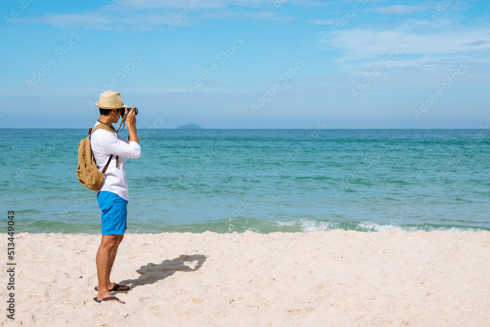 Man traveler using digital camera on summer beach blue sky take a photo. Asian Photographer man journey relax on the beach in summertime. Man backpack shooting photo asia destination holiday trip Man traveler using digital camera on summer beach blue sky take a photo. Asian Photographer man journey relax on the beach in summertime. Man backpack shooting photo asia destination holiday trip