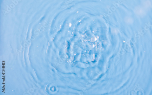 Drops fall down into clear fresh water on light blue background view from above © Виктория Попова