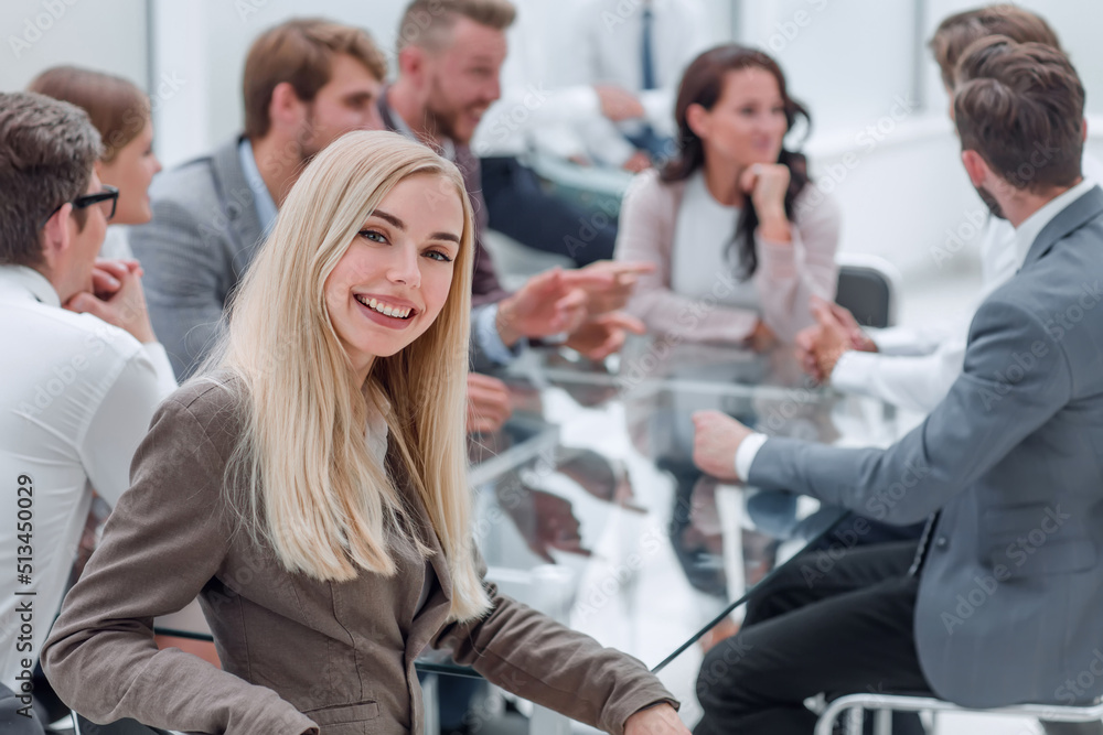Obraz premium smiling young woman sitting at table in conference room