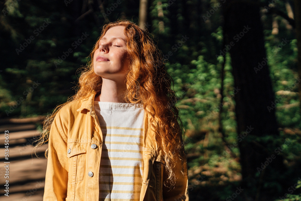 Woman with eyes closed enjoying sunlight in forest Woman with eyes closed enjoying sunlight in forest