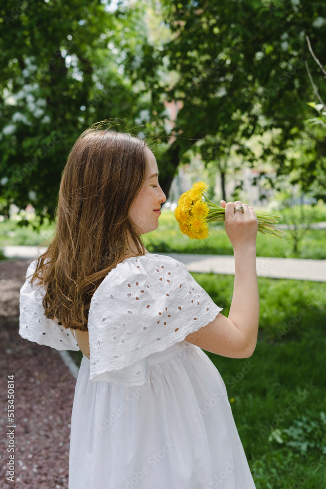 Smiling pregnant woman smelling flowers in park Smiling pregnant woman smelling flowers in park