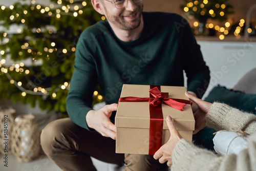 Smiling man giving gift to woman at home photo
