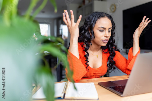 Woman gesturing and talking on video call over laptop at home office photo
