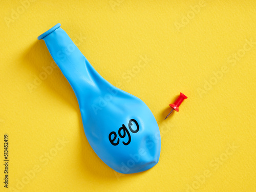 Deflated blue balloon with the word ego and a pin. Selfishness or regression of the extreme ego photo