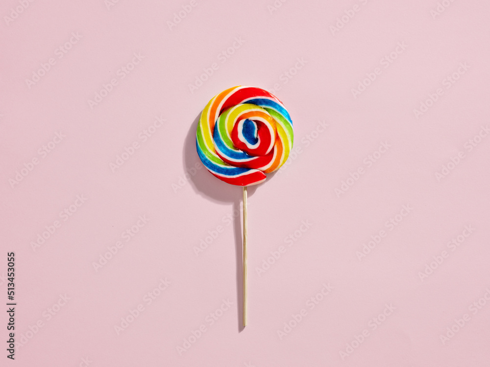 Rainbow colored swirl round candy lollipop on pink background. Rainbow colored swirl round candy lollipop on pink background.