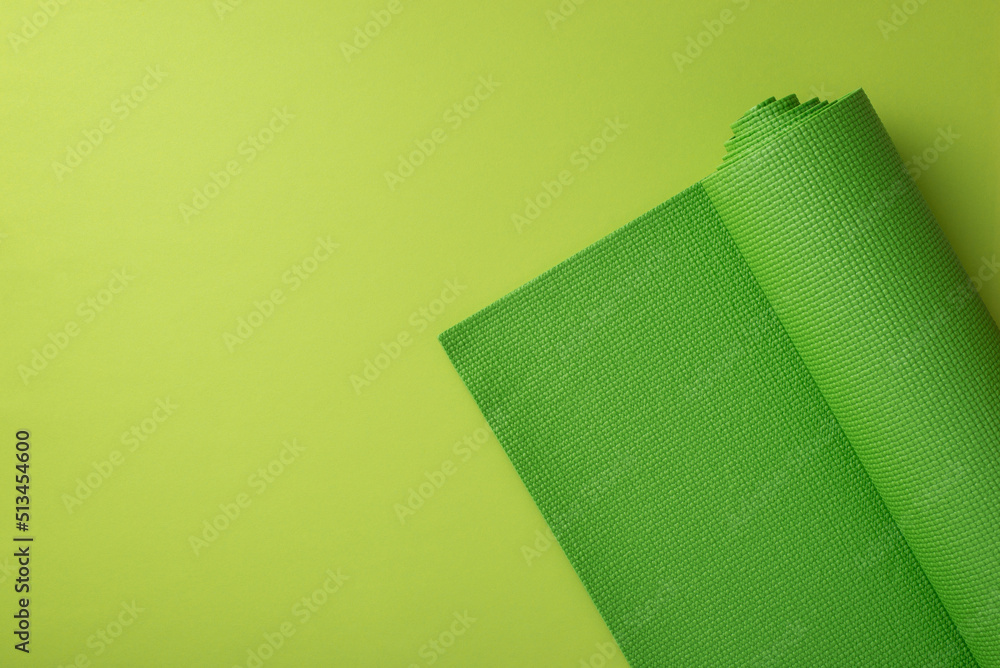Sports accessories concept. Top view photo of green yoga mat on isolated green background with copyspace - obrazy, fototapety, plakaty 