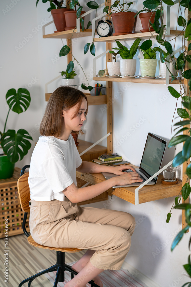 Young woman entrepreneur working on laptop at home. Freelancer typing email on a laptop, girl using a computer for study online at home, female user busy on a distance internet job. Remote online work Young woman entrepreneur working on laptop at home. Freelancer typing email on a laptop, girl using a computer for study online at home, female user busy on a distance internet job. Remote online work