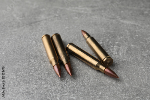 Bullets on light grey table, closeup. Firearm ammunition