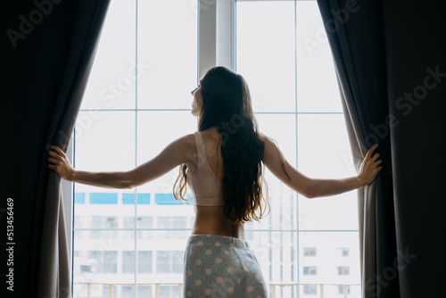 Close-up of a young woman opens the curtains in the bedroom. The concept of morning awakening
