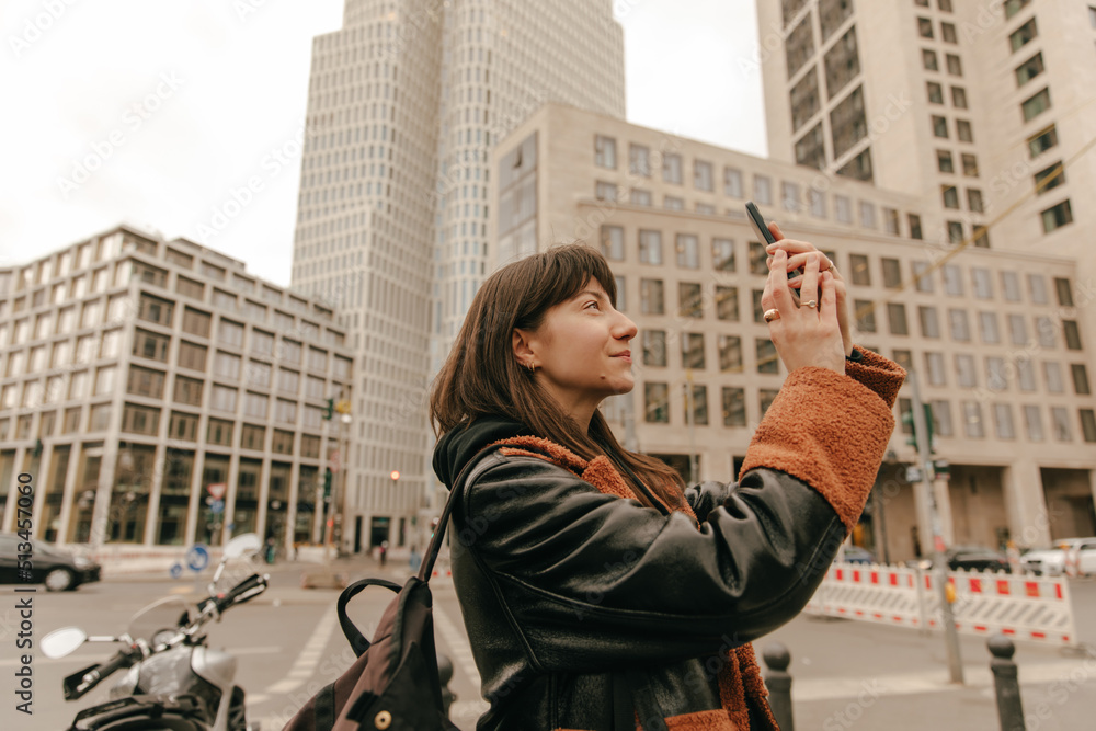The side view of woman walking in the town and look at phone The side view of woman walking in the town and look at phone
