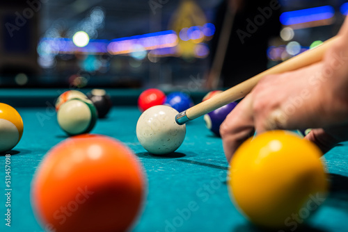 Billiard balls on the pool table with player's hands and stick.