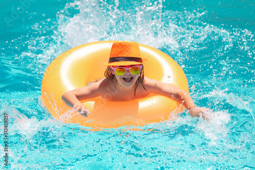 Child boy in swimming pool with inflatable ring. Kids swim in water pool on summer vacation. Swim for child on float. Beach sea and water fun.