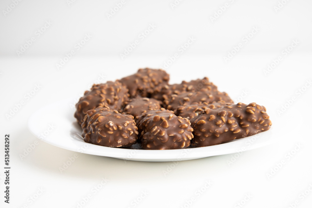 Chocolate candy bars lie on a white plate on a white background Chocolate candy bars lie on a white plate on a white background