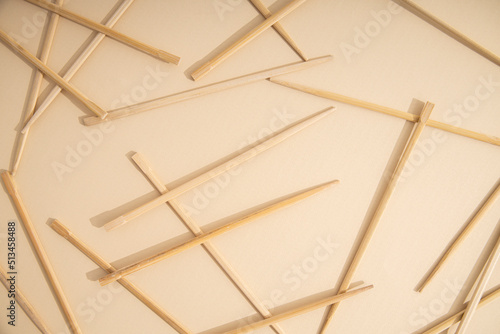 Many Chinese sticks lie on a light sandy background. Top view, flat lay