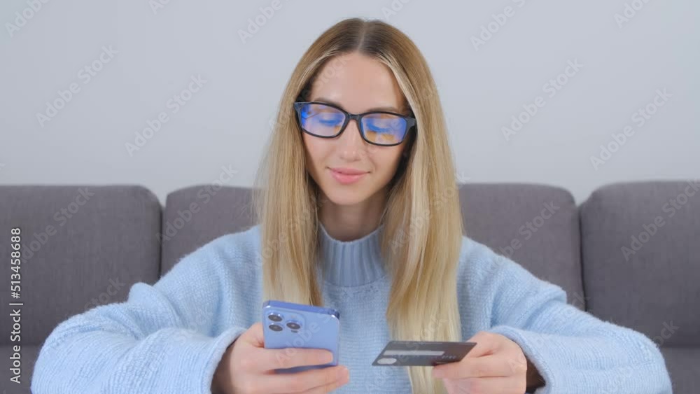 Woman buying online with a credit card. Blonde female person in glasses making a mobile payment Woman buying online with a credit card. Blonde female person in glasses making a mobile payment