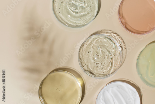Different skincare products in Petri dishes and shadow on yellow background. Flat lay