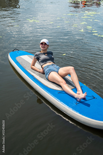 smiling woman sitting on sup board with paddle © RomanR
