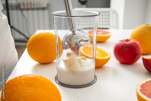 Black hand blender being used to make fresh fruit smoothie in the kitchen