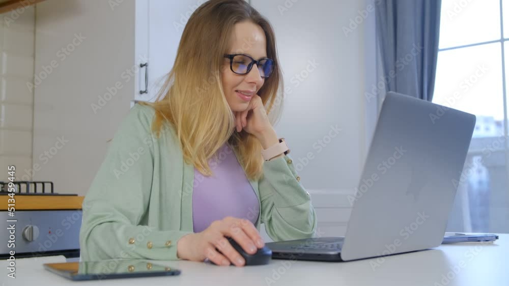 Ukrainain woman working on computer at home. Freelancer copy writer doing distant work online. Cheerful blonde female in 40s using laptop Ukrainain woman working on computer at home. Freelancer copy writer doing distant work online. Cheerful blonde female in 40s using laptop