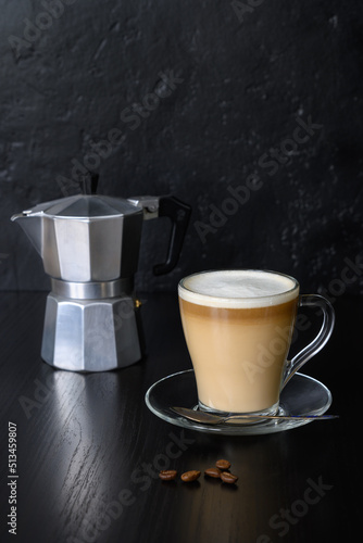 Beans, coffee in glass cup and coffee maker on a dark background