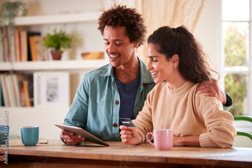 Couple With Credit Card At Home Use Digital Tablet To Review Finances For Starting Business