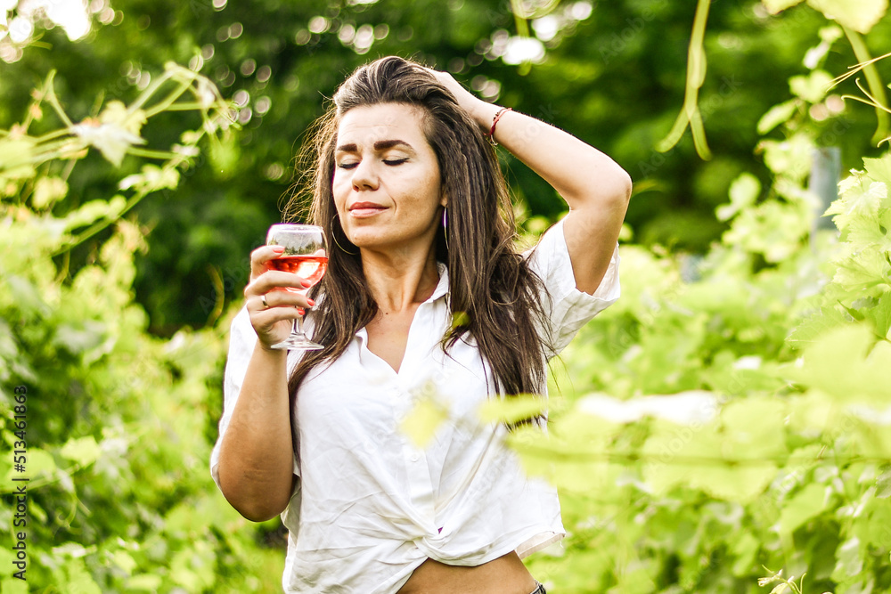 Young beautiful smiling woman in a Vineyard with a glass of rose wine during the summer vacation. Wine tourism Young beautiful smiling woman in a Vineyard with a glass of rose wine during the summer vacation. Wine tourism