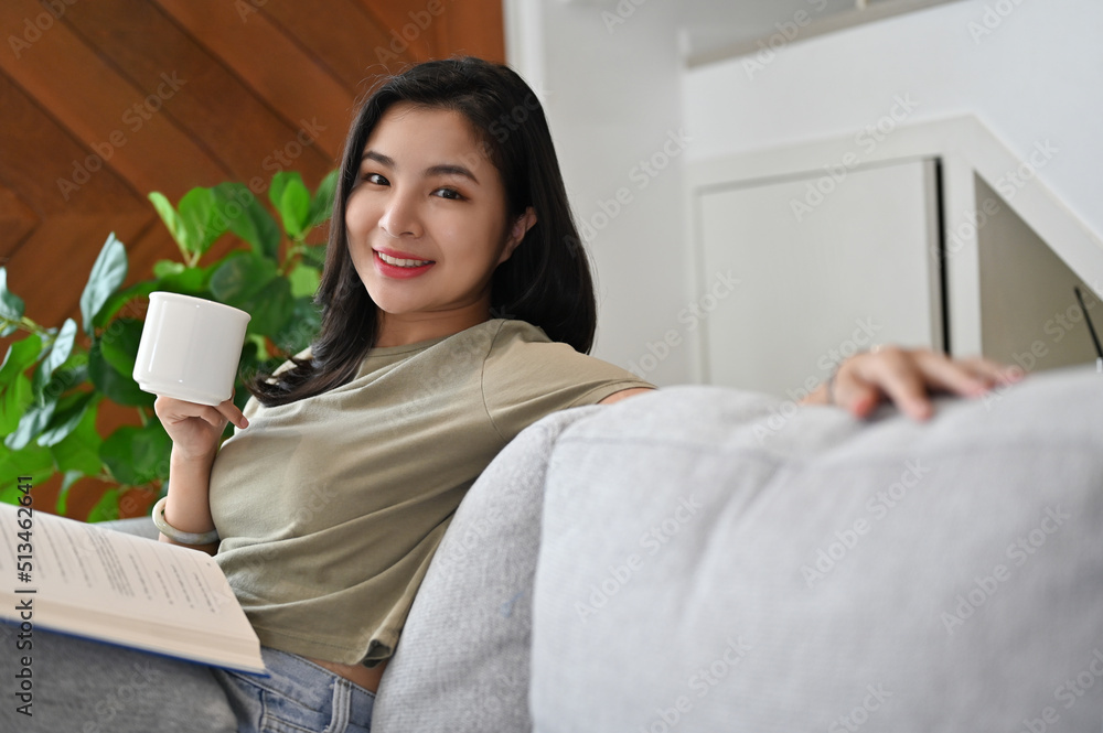 Attractive young asian woman relaxes leaning on sofa in the living room. Attractive young asian woman relaxes leaning on sofa in the living room.