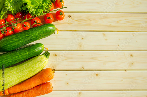 Fresh farm vegetables are laid out on a wooden tabletop. Rustic style, diet food, veganism, harvest. Text space, copy space, flat lay