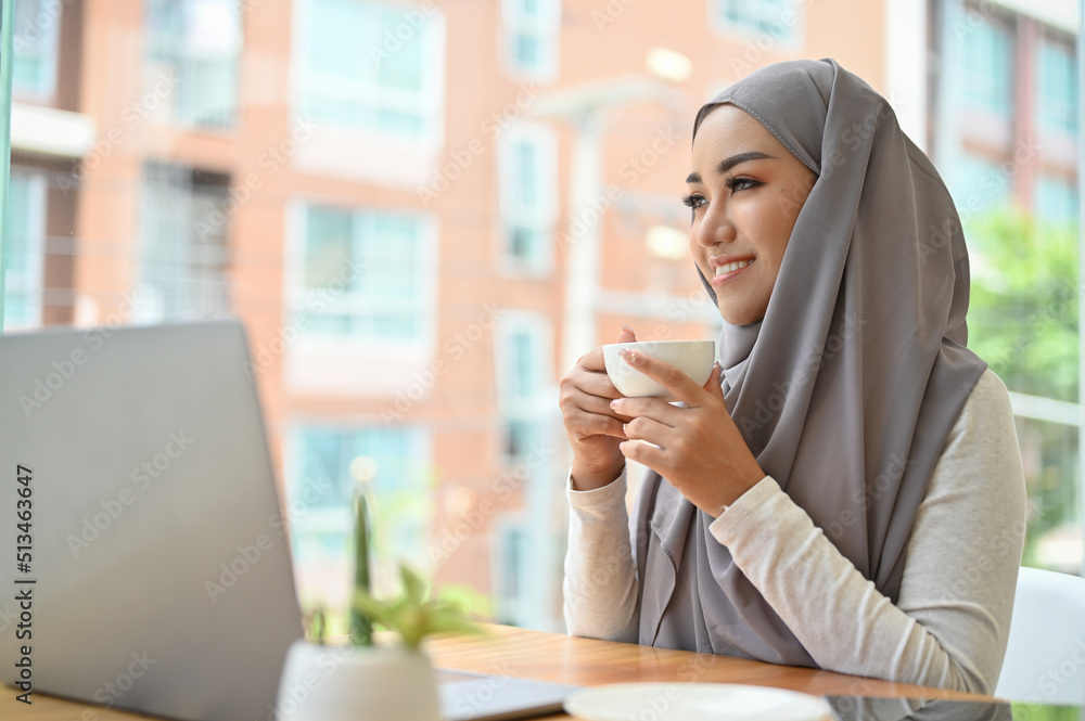 Beautiful asian muslim businesswoman with hijab relaxes sipping morning coffee. Beautiful asian muslim businesswoman with hijab relaxes sipping morning coffee.