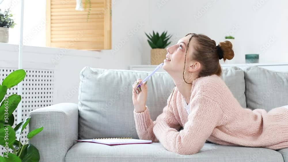 portrait of an attractive woman writing in a notebook on the couch portrait of an attractive woman writing in a notebook on the couch