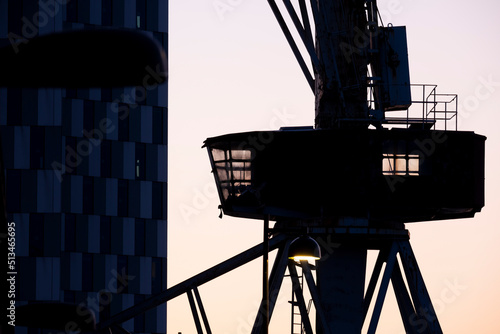 A silhouette of an old shipyard crane against the sunset