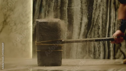 Old stone age large hammer hitting floor and spraying dust . Viking man hitting floor with huge sledgehammer. Strength and durability concept . Shot on ARRI Alexa cinema camera in 200fps Slow motion photo