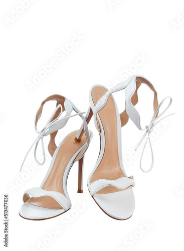 Pair of elegant women's open snow-white leather strappy sandals tied with a bow, with a high thin heel, isolated on a white background. The bride's shoes for the wedding ceremony. photo