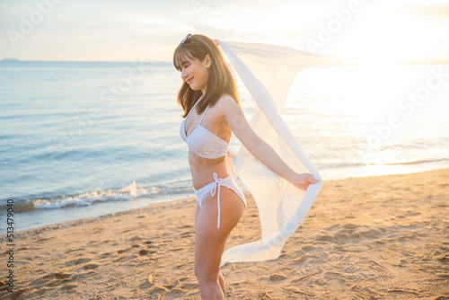 Young beautiful woman wear bikini swimsuit with blowing sarong enjoying walking and spin body at tropical beach, Happy Asian sexy female have fun holiday outside, Summer travel vacation relaxing
