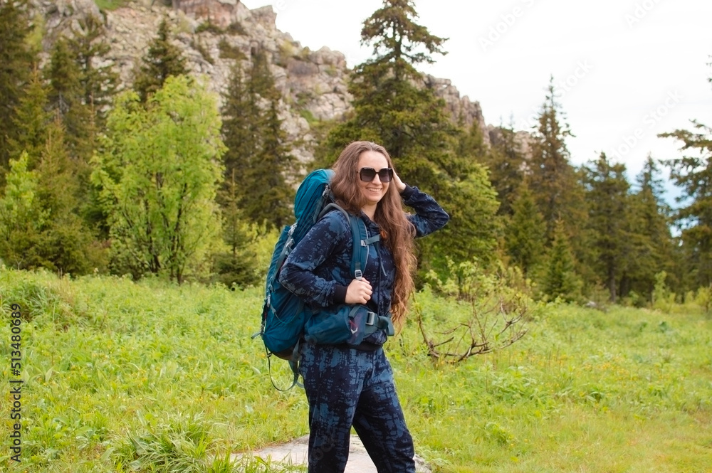 young female traveler with a backpack looks at the mountains. Hiking is an active lifestyle of people wearing a backpack, exercising outdoors. Selective focus