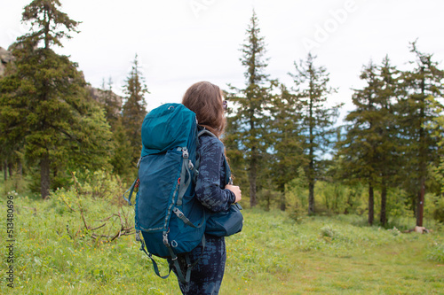 young female traveler with a backpack looks at the mountains. Hiking is an active lifestyle of people wearing a backpack, exercising outdoors. Selective focus