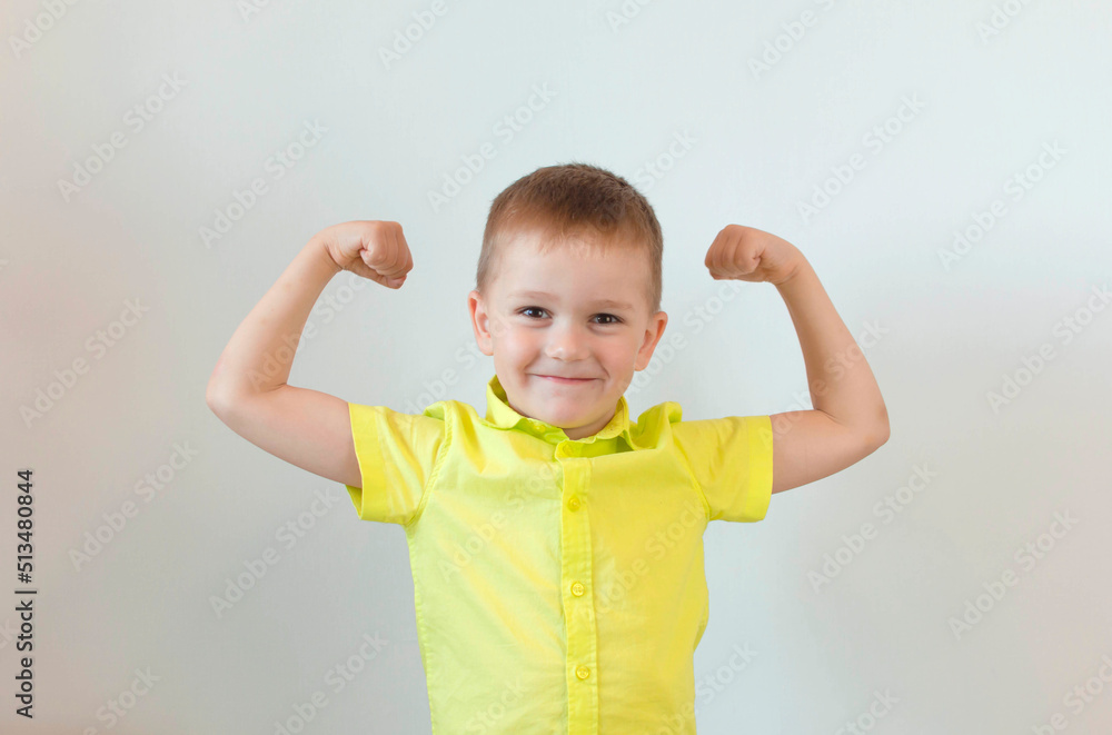 A five-year-old child in a green shirt poses on a white background feeling strong and full of energy. The concept of the lifestyle of people with sincere emotions. To raise strong children A five-year-old child in a green shirt poses on a white background feeling strong and full of energy. The concept of the lifestyle of people with sincere emotions. To raise strong children