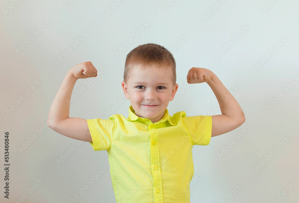 A five-year-old child in a green shirt poses on a white background feeling strong and full of energy. The concept of the lifestyle of people with sincere emotions. To raise strong children A five-year-old child in a green shirt poses on a white background feeling strong and full of energy. The concept of the lifestyle of people with sincere emotions. To raise strong children