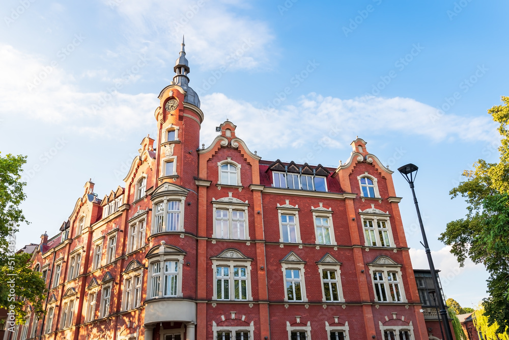 Obraz premium The building of the town hall from 1904. Red brick facade. Beautiful blue sky. The richly decorated facade of the tenement house. Siemianowice Śląskie, Poland