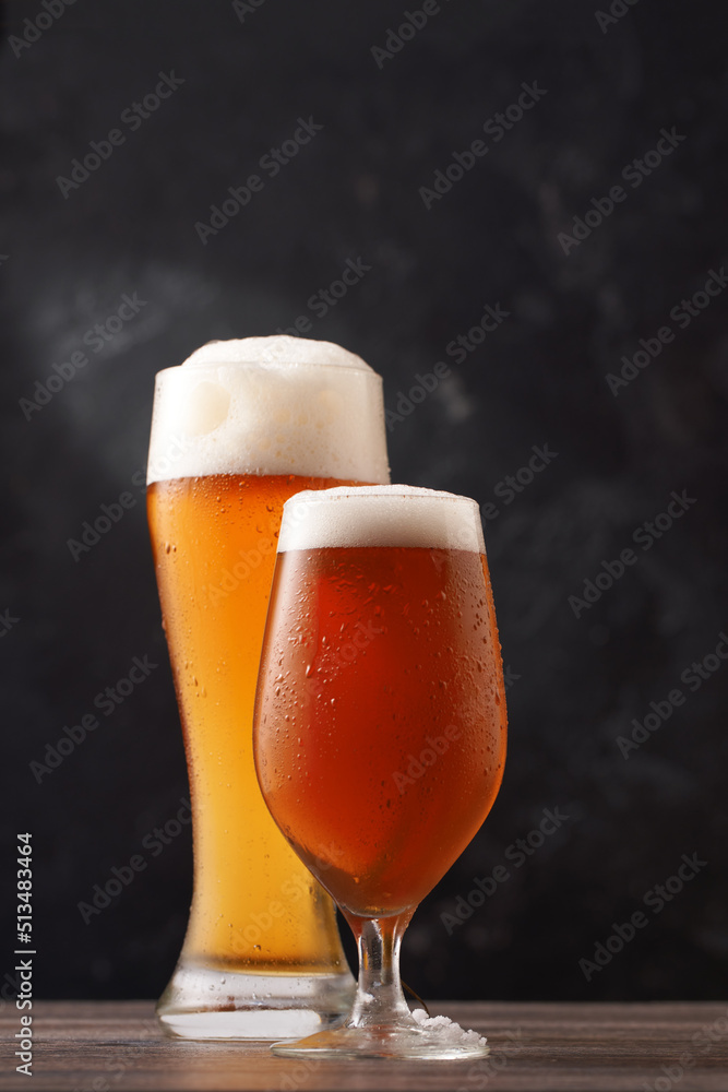Two glasses of beer on black background.