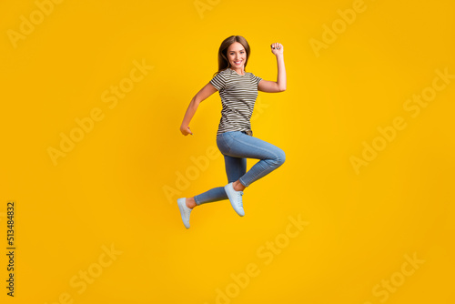 Fill body portrait of overjoyed delighted girl jump raise fists celebrate success isolated on yellow color background