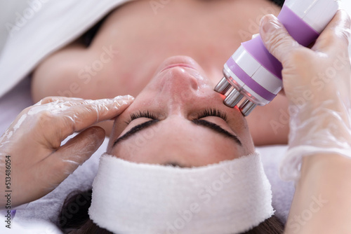 A young woman undergoing a facial radiofrequency face lift treatment. Facial skin care treatment, anti-aging facial rejuvenation. Beauty and dermatology concept.