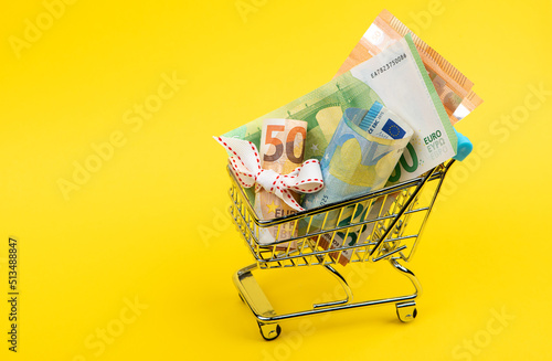 small market handcart with a euro money banknotes on a yellow isolated background close up