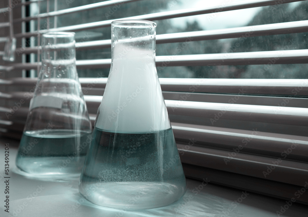 Two flasks with reagents. In a chemical experiment, the substances reacted and a white gas was released in the form of steam and clouds of smoke. Laboratory research. school experiments Two flasks with reagents. In a chemical experiment, the substances reacted and a white gas was released in the form of steam and clouds of smoke. Laboratory research. school experiments