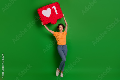 Full length photo of charming satisfied person arm hold big like collage above head isolated on green color background © deagreez