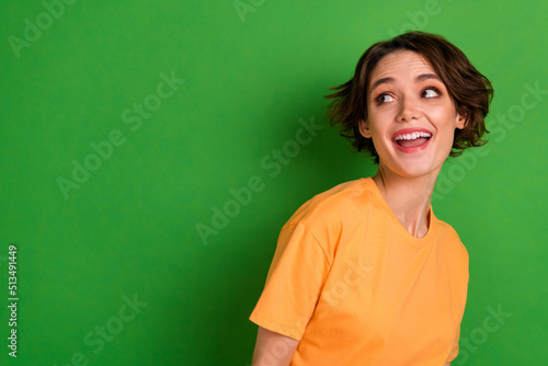 Photo of funny dreamy young woman dressed orange t-shirt looking empty space isolated green color background