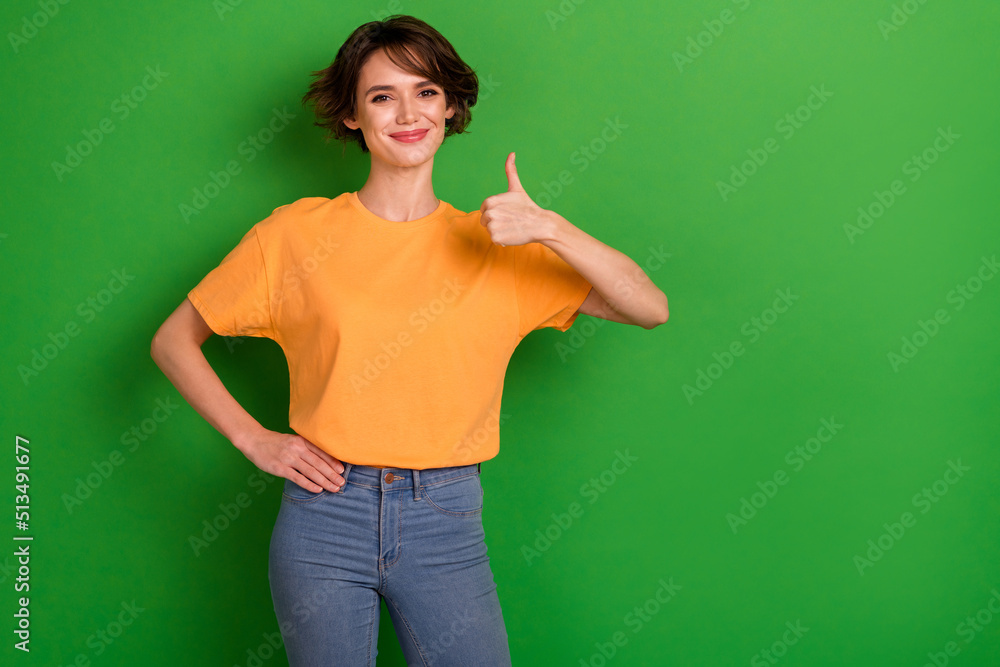 Photo of confident pretty young woman dressed orange t-shirt showing thumb up empty space isolated green color background Photo of confident pretty young woman dressed orange t-shirt showing thumb up empty space isolated green color background